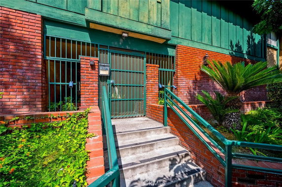 Front view of a building entrance with brick walls and metal gates.