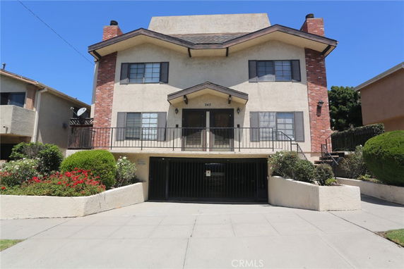 Front view of a multi-story house with a gated garage and brick accents.