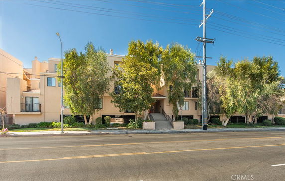 Front view of a multi-story residential building with trees in front.