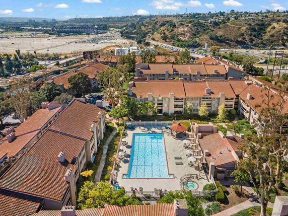 Aerial view of a residential complex with a central swimming pool and surrounding buildings with red-tiled roofs.