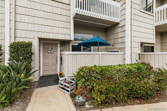 Front view of a multi-story house with a small fenced patio and balcony above.