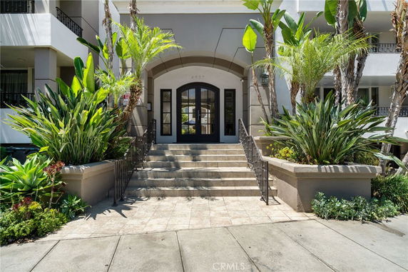 Front entrance of a multi-story building with stairs and plants.
