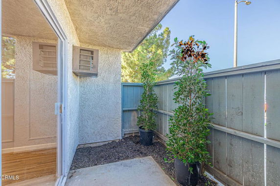 Outdoor patio area with potted plants and a wooden fence.