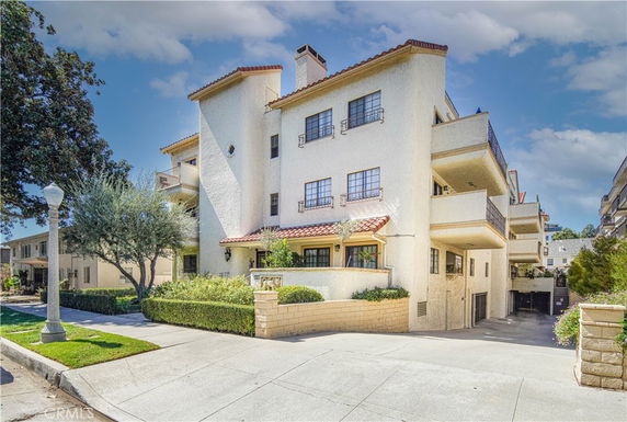 Front view of a multi-story residential building with balconies and a gated entrance.