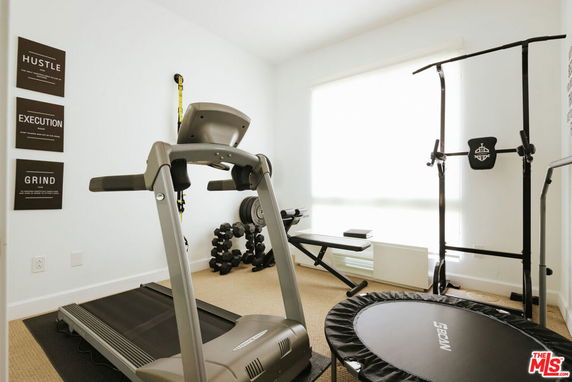 Room with exercise equipment including a treadmill and weights.