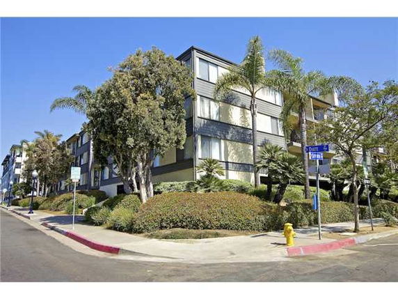 Front view of a multi-story apartment building with large windows and surrounded by trees.