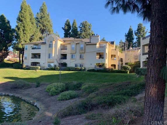 Front view of a multi-story residential building with balconies and yellow exterior.