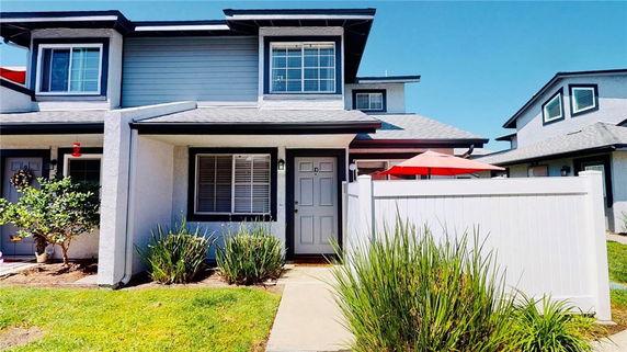 Front view of a two-story house with an entrance patio and white fence.