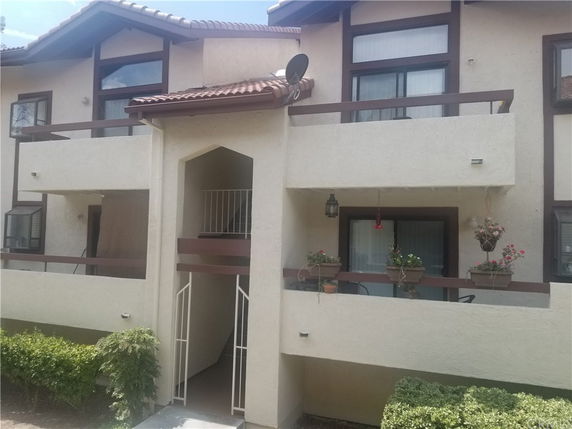 Front view of a two-story residential building with balconies and a gated entrance.
