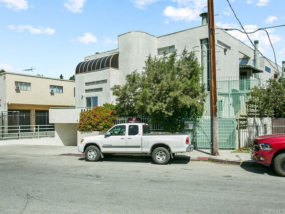 Front view of a multi-story building with a prominent curved structure on the upper floor.