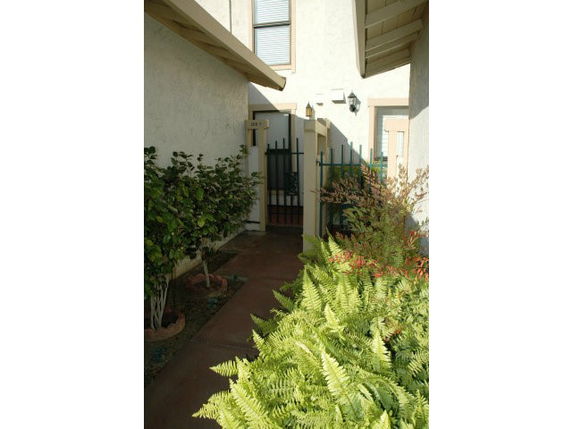 Front view of a house with a gated entrance and surrounding greenery.