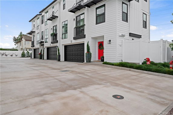 Front view of a multi-story building with multiple garages and a bright red door.