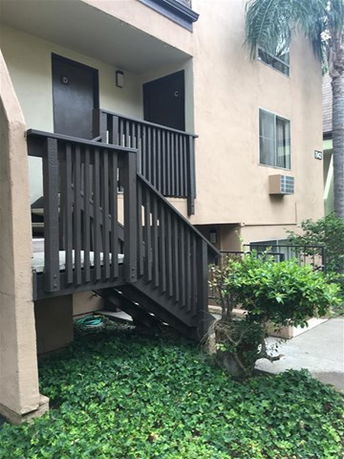 Front view of an apartment building with external staircase and entrance doors.