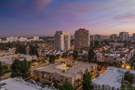 Wide aerial view of cityscape with multiple buildings during sunset.