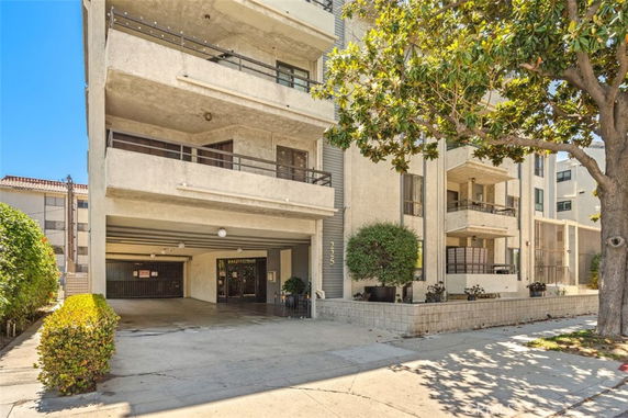 Front view of a multi-story apartment building with balconies and a covered entryway.