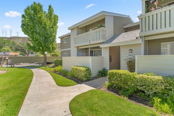 Front view of a two-story residential building with balconies and a pathway leading to the entrance.