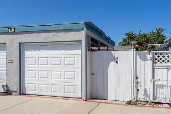 Front view of a single-story garage with an adjoining fence and gate.