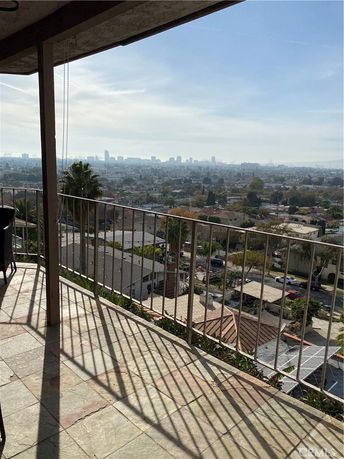 Panoramic view of cityscape from a balcony with railing.