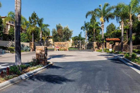Front view of a building entrance with gates and palm trees.