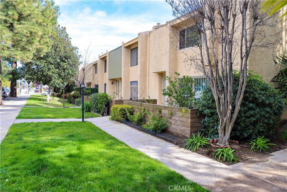 Front view of a multi-story residential building with a landscaped walkway.