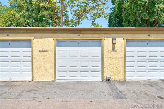 Outdoor parking area with three garage doors.