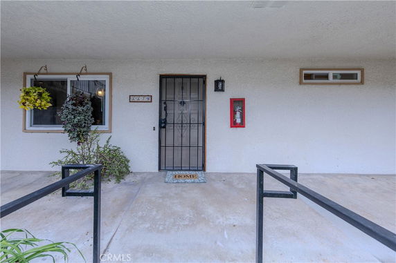 Front view of a house entrance with a metal security door and windows on either side.