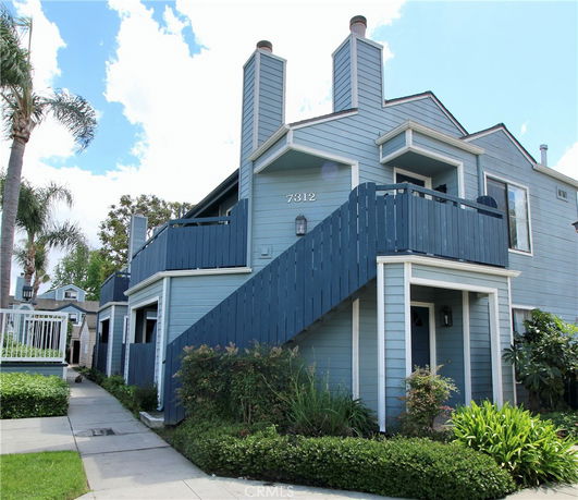 Front view of a two-story house with a balcony and staircase.