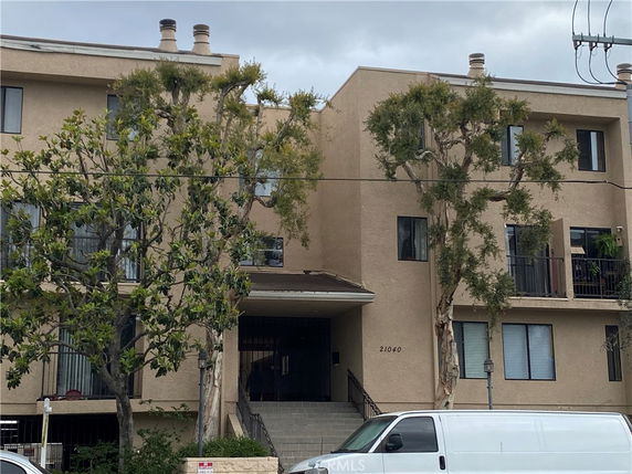Front view of a multi-story apartment building with balconies and several windows.