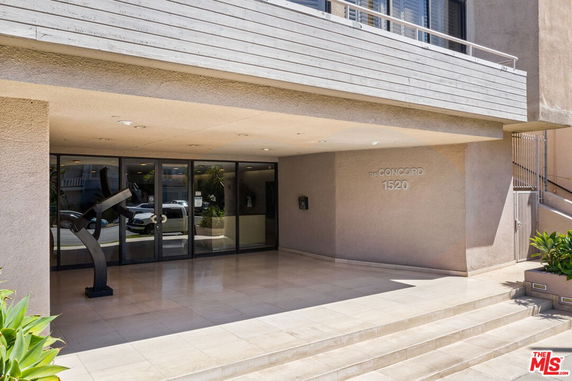 Front view of a modern building entrance with large glass doors and a sculpture.