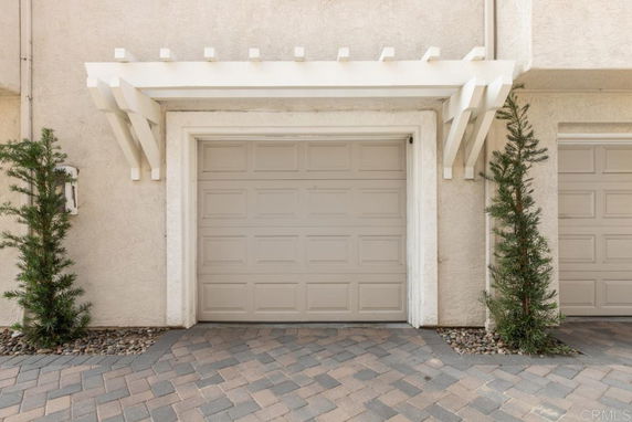Front view of a house with a single garage door and decorative white wooden trim.