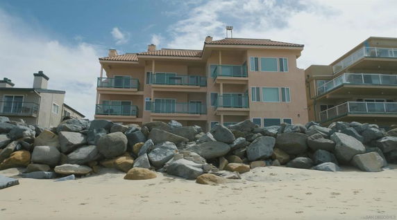 Front view of a multi-story building with balconies located on a beach.