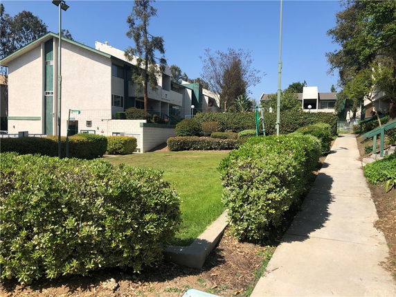 Front view of a multi-story residential building with angled roofs and a landscaped pathway.