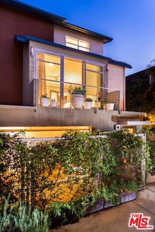 Front view of a modern multi-story house with large glass windows and a balcony.