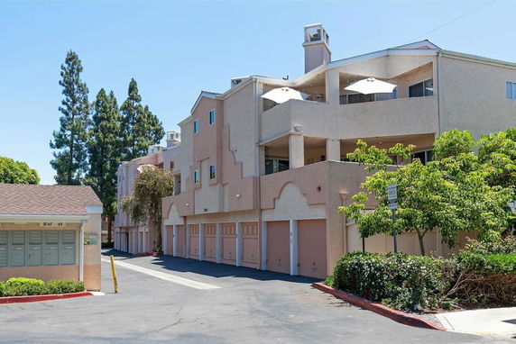Front view of a multi-story building with balconies and garages.