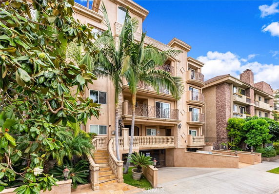 Front view of a multi-story building with balconies and decorative railing.