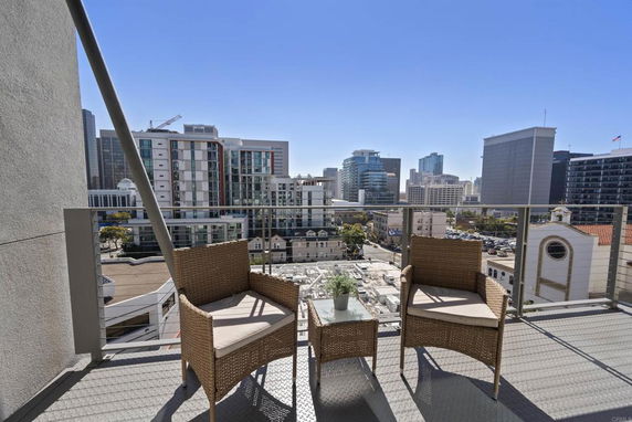View from a balcony with two chairs overlooking urban buildings.