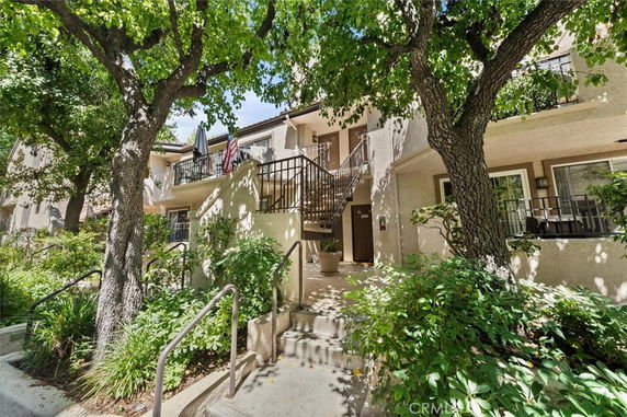 Front view of a multi-story residential building with stairway entrance and balconies.