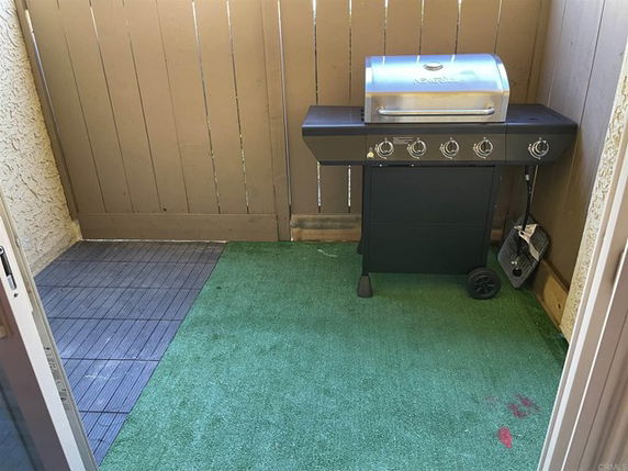 Outdoor space with a barbecue grill and artificial turf.