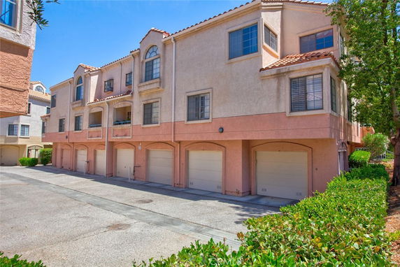 Front view of a multi-story residential building with garages on the ground floor.