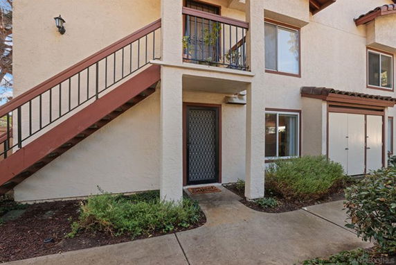Front view of a two-story building with an external staircase and covered entrance.