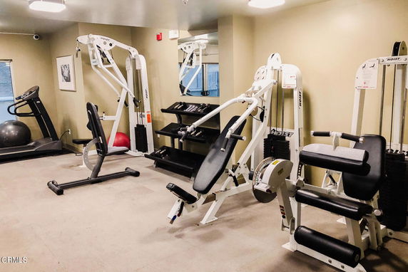 Indoor gym area with exercise equipment and weights.