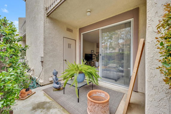 View of a building's exterior with a sliding glass door and small patio area.
