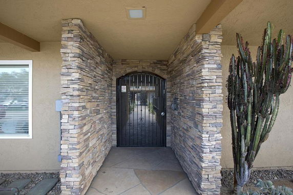 Front entrance of a house with stone wall accents and an arched metal door.