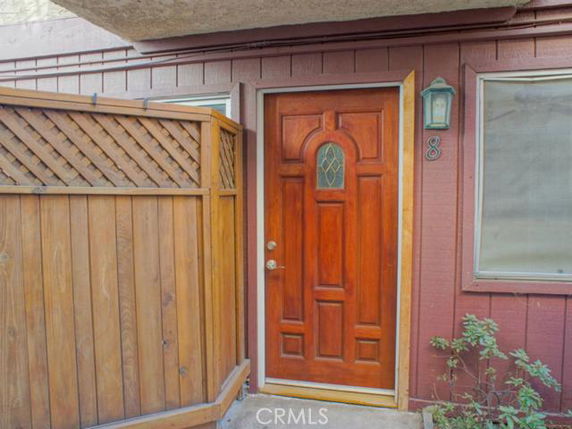Front view of a house entrance with a wooden door and adjacent wooden privacy screen.