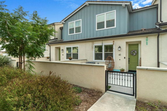 Front view of a townhouse with two stories, featuring a gated entrance and a green front door.
