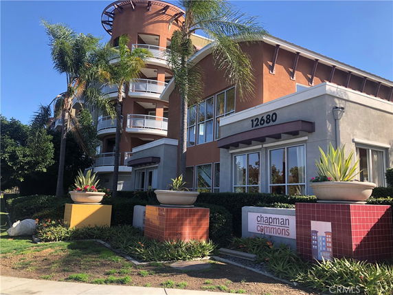 Front view of a multi-story building with balconies and large planters.