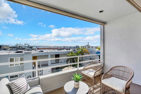 View from a balcony overlooking residential buildings with a distant view of the ocean.