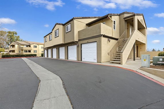 Front view of a two-story building with multiple garage doors and an exterior staircase.