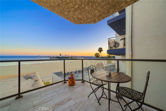 Balcony view overlooking the beach and ocean at sunset.