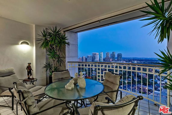 Panoramic view from a balcony overlooking a city skyline at dusk.